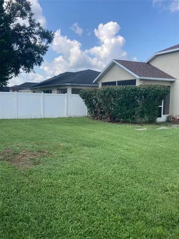 a view of a house with a yard and a large tree