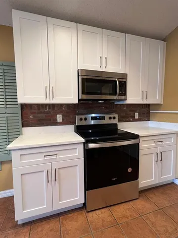 a kitchen with granite countertop white cabinets and stainless steel appliances