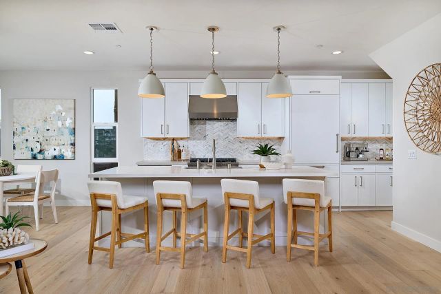 a kitchen with stainless steel appliances granite countertop a stove a sink a dining table and chairs with wooden floor