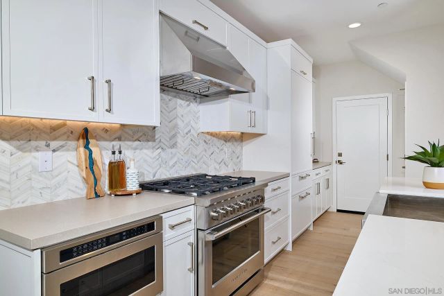 a kitchen with stainless steel appliances a stove and white cabinets