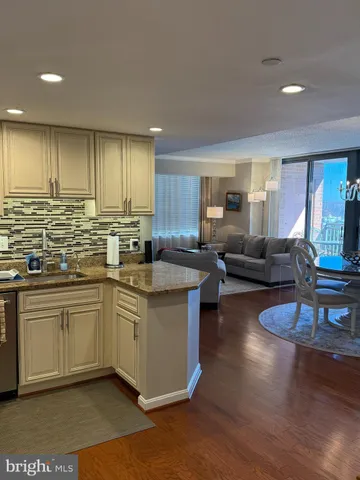 a kitchen with granite countertop a stove a sink a refrigerator dining table and chairs