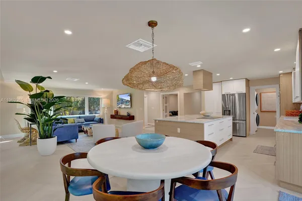 a dining room with furniture a potted plant and kitchen view