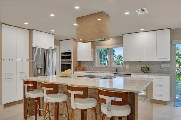 a kitchen with stainless steel appliances granite countertop a table chairs sink and cabinets