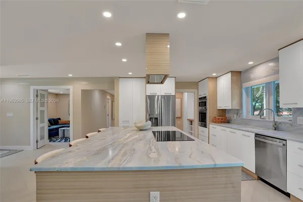 a large kitchen with stainless steel appliances kitchen island a stove a sink a refrigerator and a counter top space
