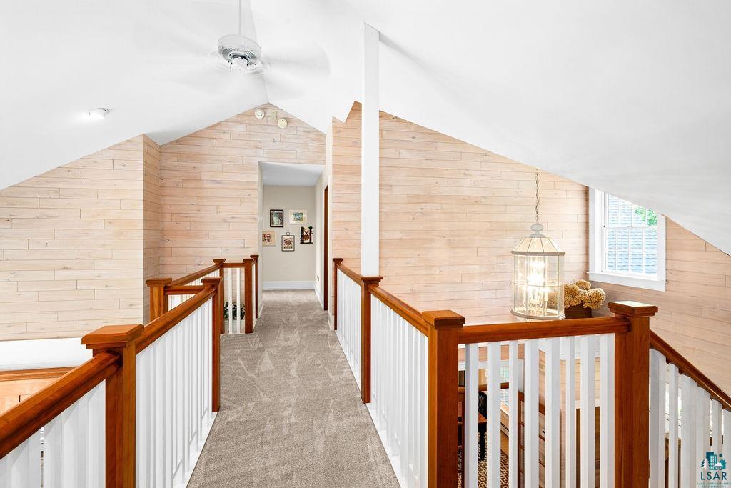3168 Pioneer Road Barnum, MN 55707 - Photo 31 of 46 Walkway with vaulted ceiling, wood walls, and newly laid carpet. The banisters are maple with white wood, leading to two more upper level bedrooms.