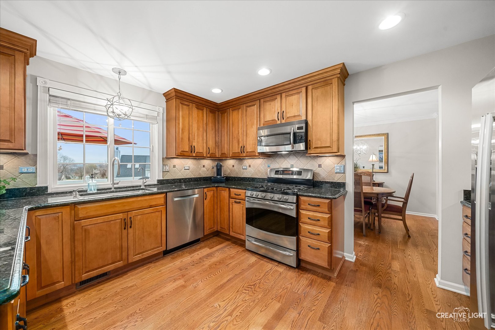 7 Falcon Ridge Court Algonquin, IL 60102 - Photo 10 of 51 a kitchen with stainless steel appliances granite countertop a stove top oven a sink dishwasher a dining table and chairs with wooden floor