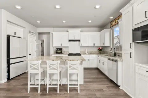 a kitchen with stainless steel appliances granite countertop a stove top oven a sink dishwasher a dining table and chairs with wooden floor