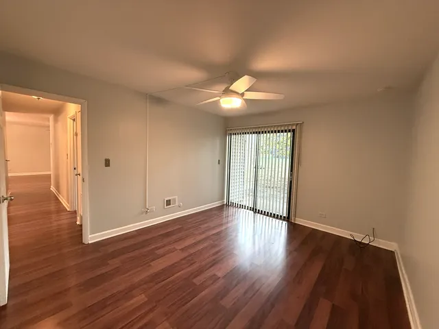 a view of an empty room with window and wooden floor