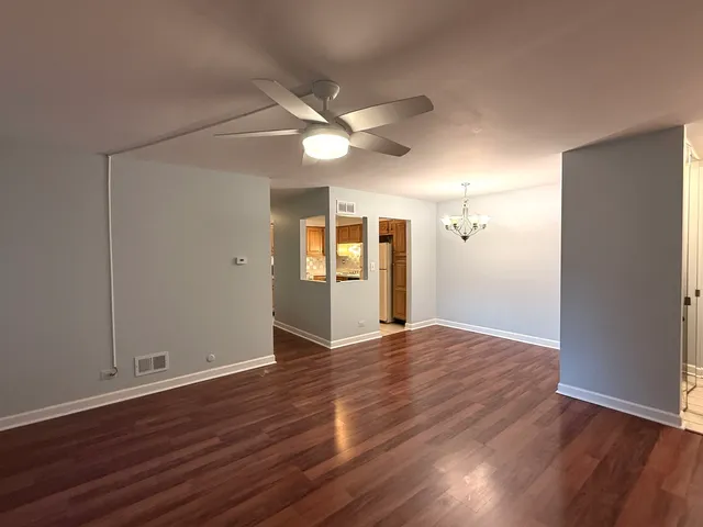 an empty room with wooden floor and a ceiling fan