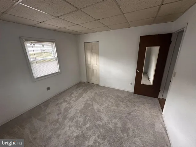 a view of an empty room with window and closet area