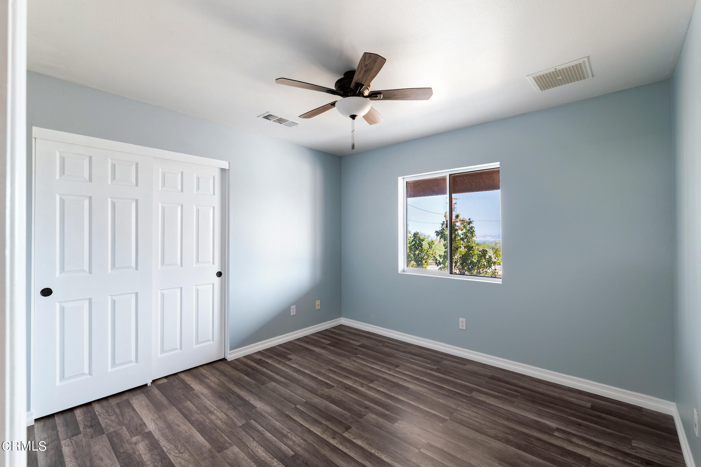6864 Sunnyhill Road Joshua Tree, CA 92252 - Photo 36 of 71 an empty room with wooden floor chandelier fan and windows