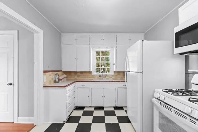 a kitchen with a sink a refrigerator and white cabinets