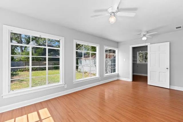 a view of an empty room with a window and wooden floor