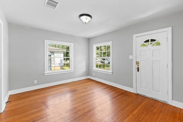 an empty room with window and wooden floor
