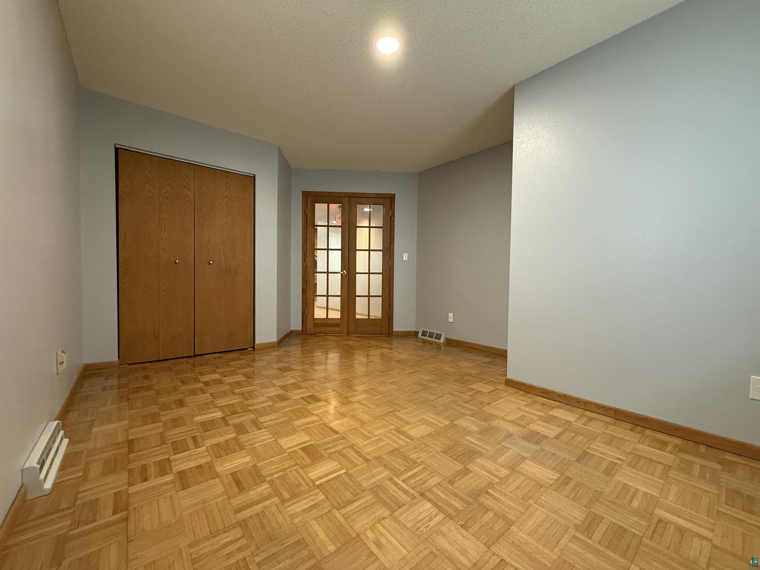 1321 South 13th Street Virginia, MN 55792 - Photo 16 of 33 Unfurnished bedroom with french doors, a closet, parquet floors, and a textured ceiling