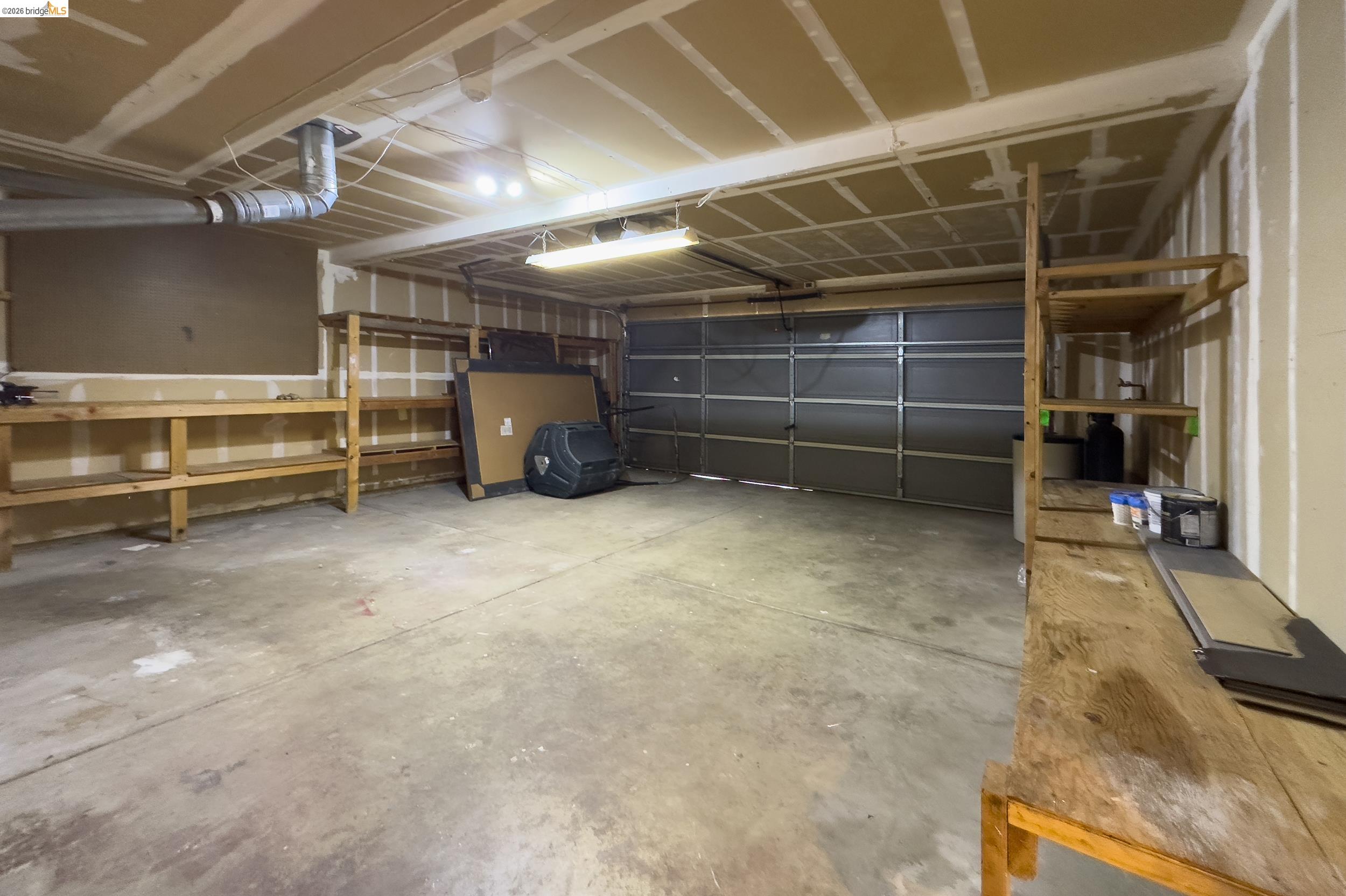 512 Burdick Drive Bay Point, CA 94565 - Photo 49 of 50 Spacious garage featuring a concrete floor, built-in wooden shelving units, and a sectional overhead garage door
