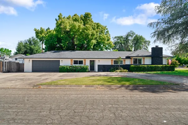 a front view of house with yard and trees in the background
