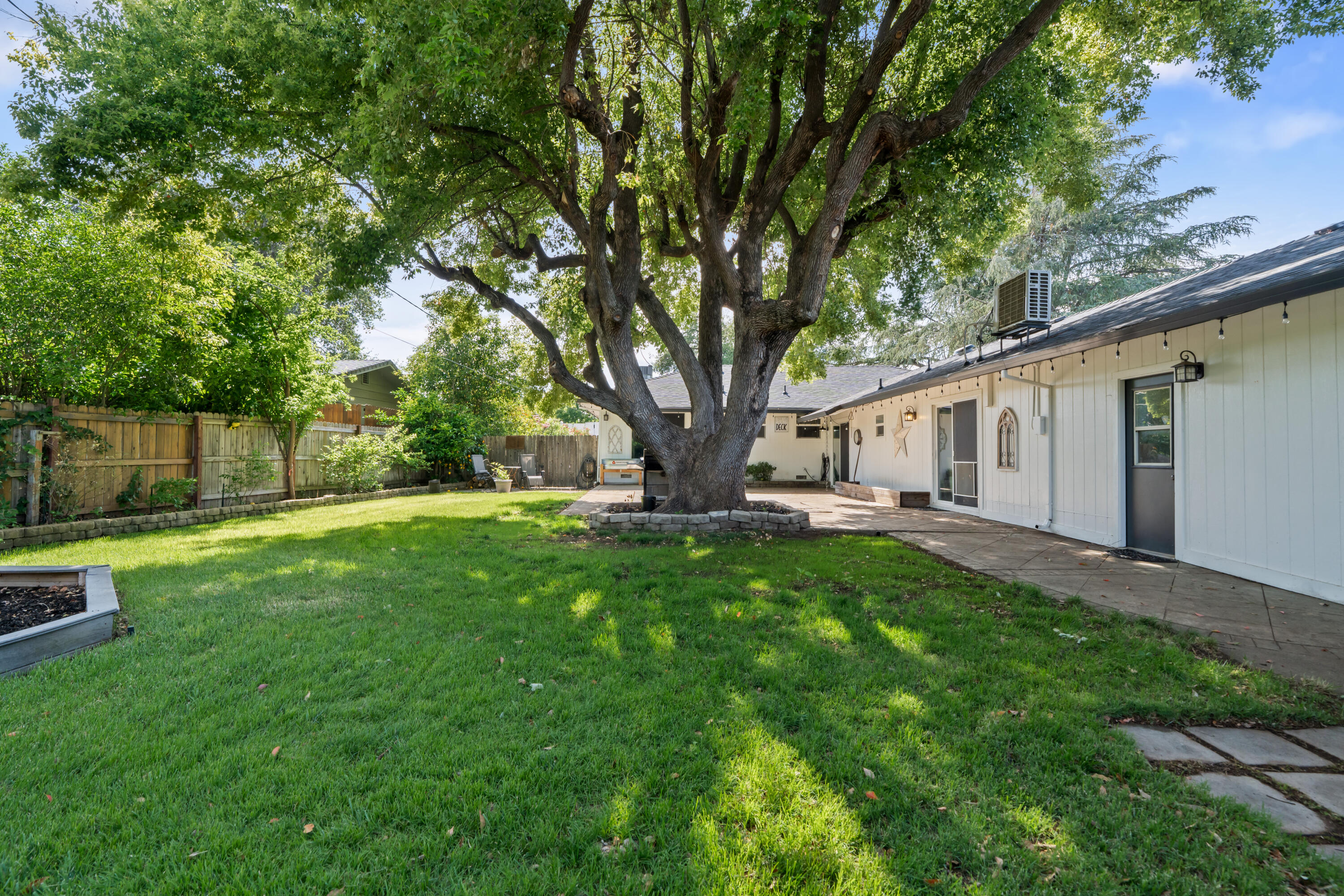 3689 Suzanne Way Redding, CA 96002 - Photo 42 of 46 a view of a white house in front of a big yard with large trees and wooden fence