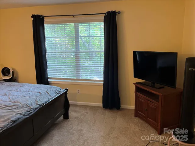 a bedroom with a bed and a flat tv screen on dresser