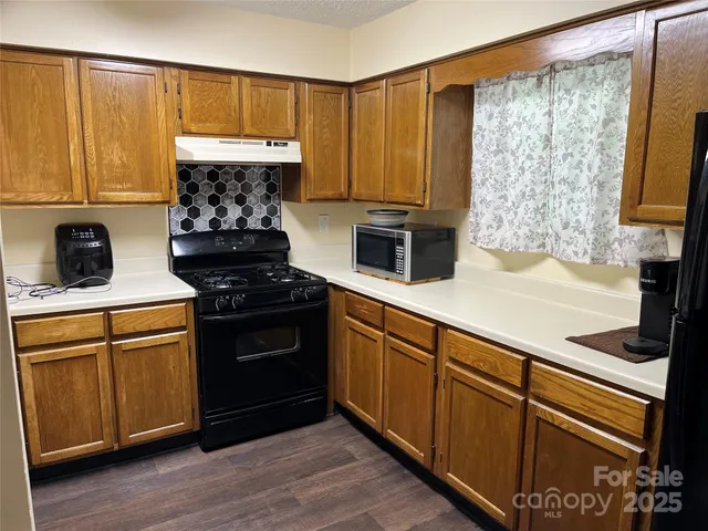 a kitchen with stainless steel appliances granite countertop a stove a sink and a microwave