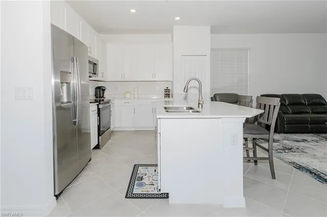 a kitchen with stainless steel appliances kitchen island a refrigerator sink and cabinets