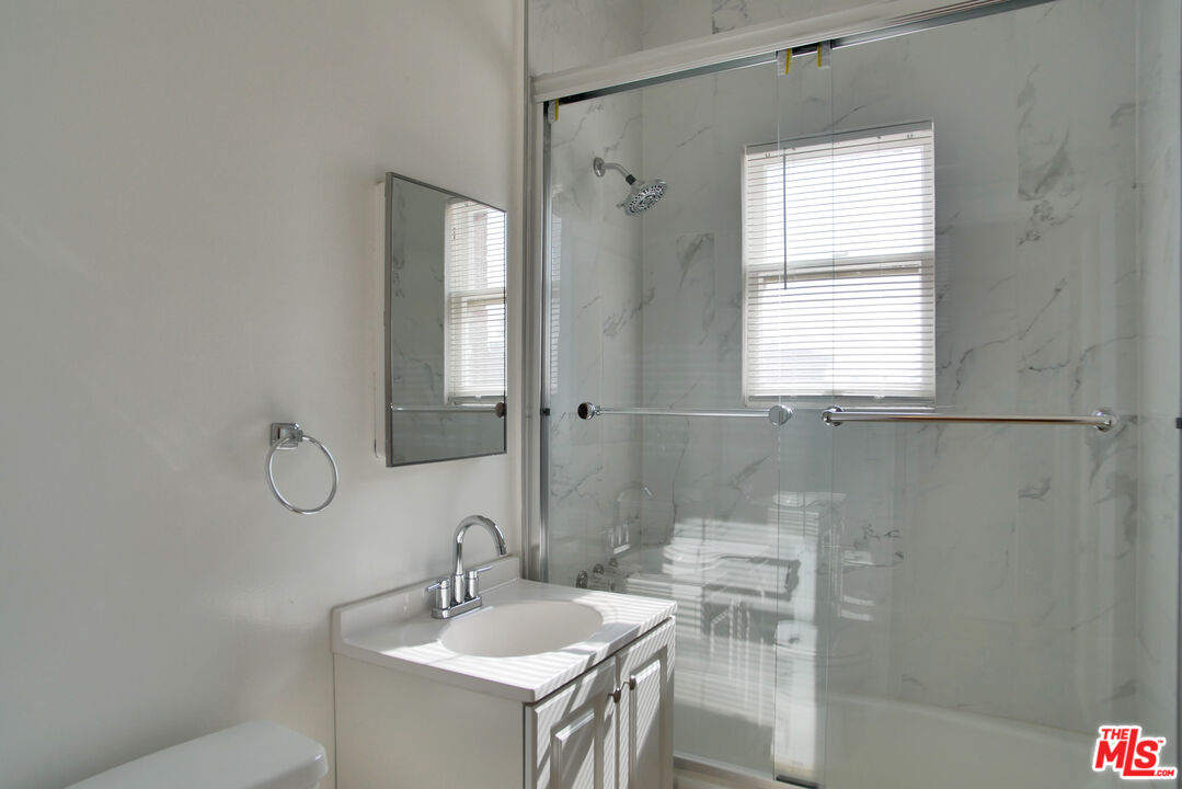 611 South Cloverdale Avenue, Unit 305 Los Angeles, CA 90036 - Photo 18 of 18 a bathroom with a granite countertop sink a mirror and a shower