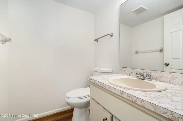 a bathroom with a granite countertop sink and a toilet