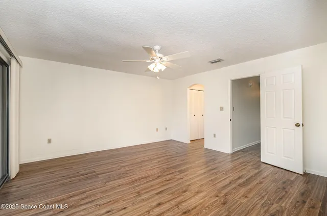 an empty room with wooden floor and ceiling fan