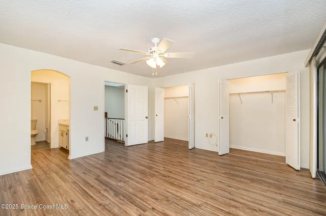 an empty room with wooden floor and a ceiling fan