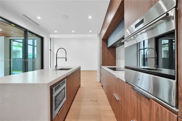 a large kitchen with stainless steel appliances a sink and cabinets