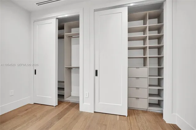 a view of empty room with wooden floor and closet