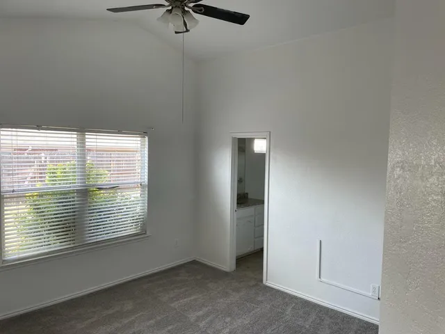 an empty room with a window and a fan