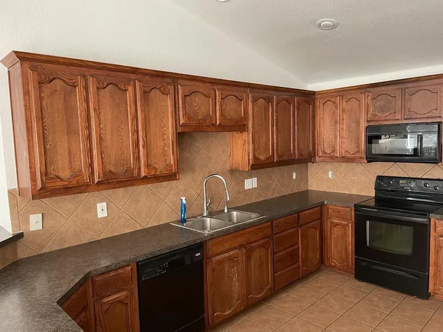 a kitchen with granite countertop a stove sink and cabinets