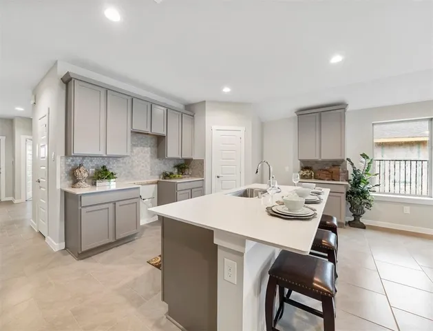 a kitchen with a dining table chairs sink and white cabinets