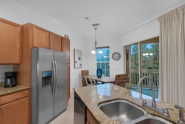 a kitchen with stainless steel appliances granite countertop a sink a refrigerator and a granite counter tops