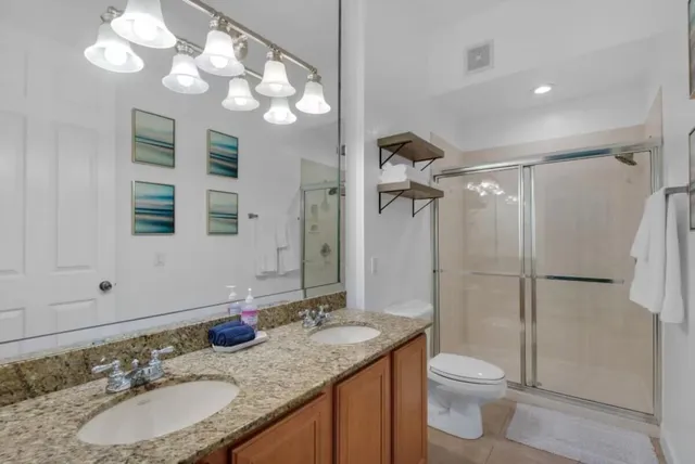 a bathroom with a granite countertop sink toilet a mirror a vanity and shower