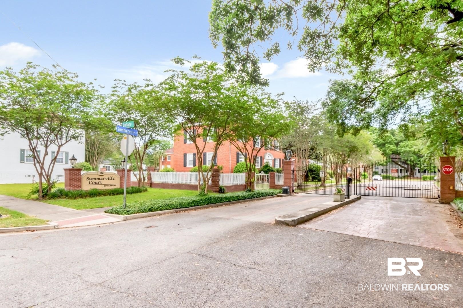 214 Upham Street, Unit 3D Mobile, AL 36607 - Photo 23 of 34 View of asphalt road featuring a gate, traffic signs, a gated entry, curbs, and a residential view