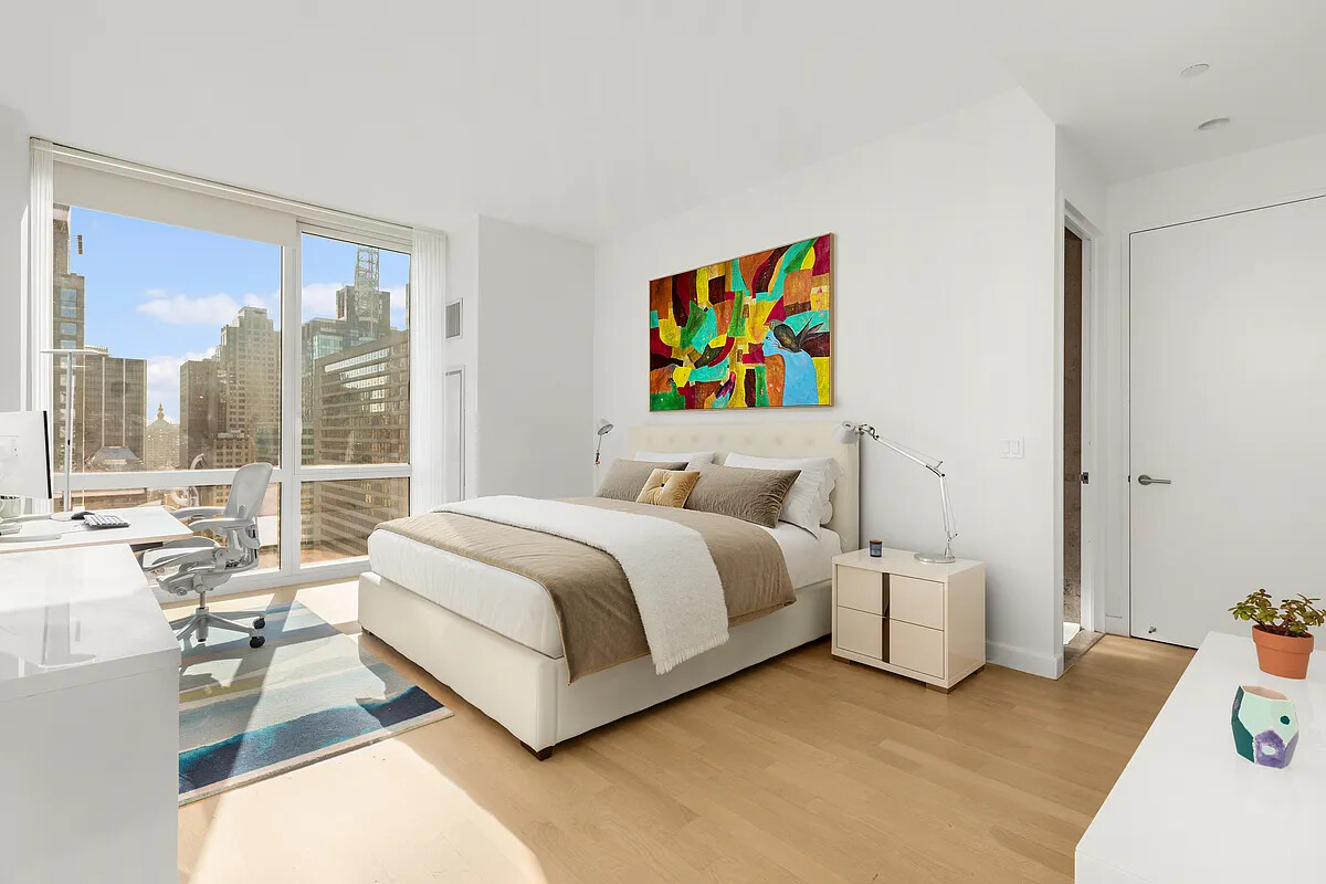 247 West 46th Street, Unit 4104 Manhattan, NY 10036 - Photo 4 of 7 a spacious bedroom with a bed and a large window