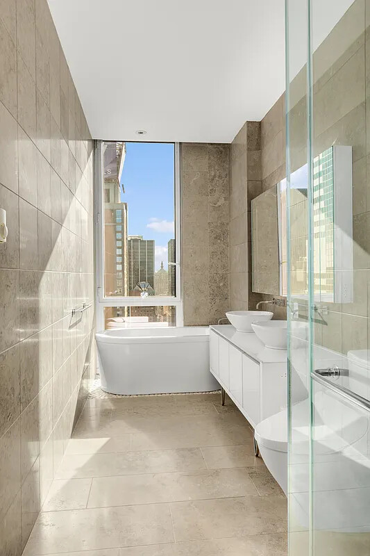 247 West 46th Street, Unit 4104 Manhattan, NY 10036 - Photo 5 of 7 a bathroom with a tub sink and shower