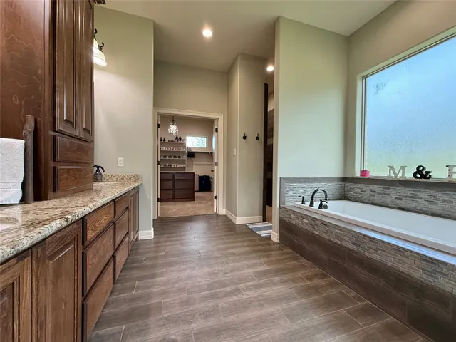 a large bathroom with a granite countertop double vanity sink a bathtub and mirror