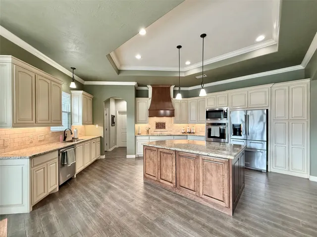 a large kitchen with a large island in the center and stainless steel appliances