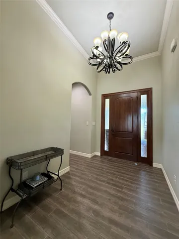 a view of a hallway with wooden floor and a chandelier