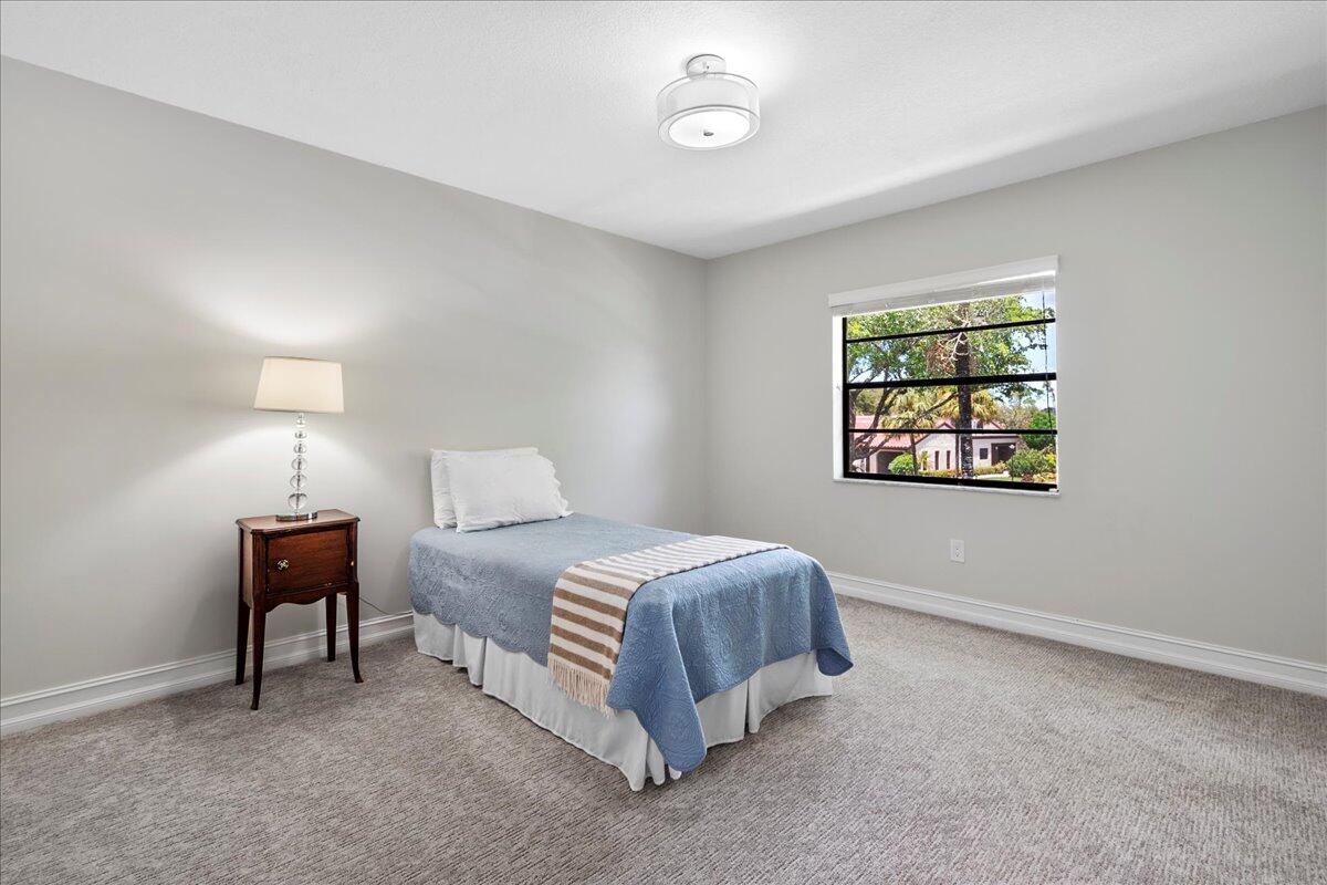 21719 Arriba Real, Unit J Boca Raton, FL 33433 - Photo 17 of 33 a spacious bedroom with a bed and a lamp on the dresser