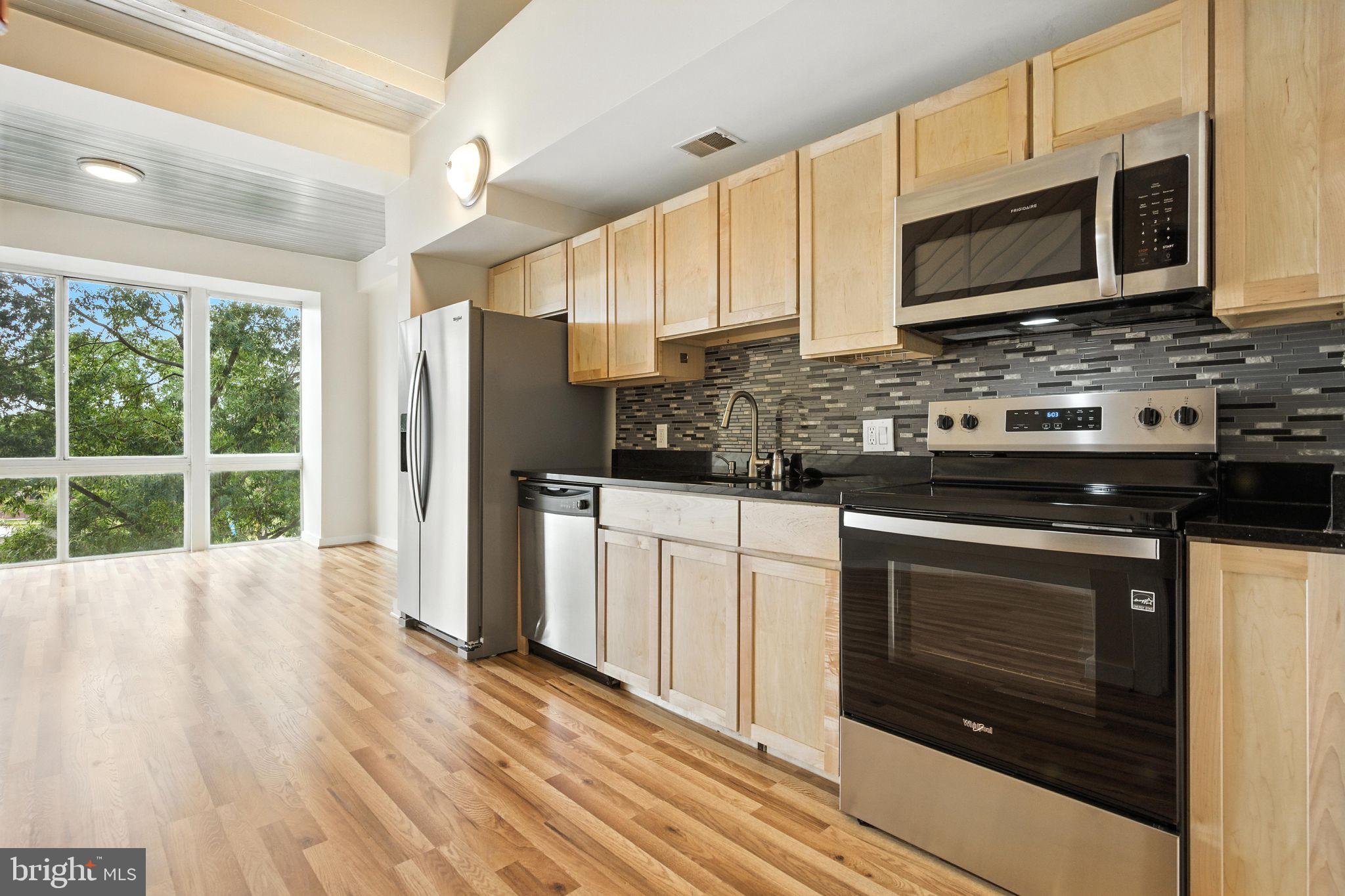 5885 Colorado Avenue Northwest, Unit 208 Washington, DC 20011 - Photo 13 of 27 a kitchen with stainless steel appliances a stove sink microwave and cabinets
