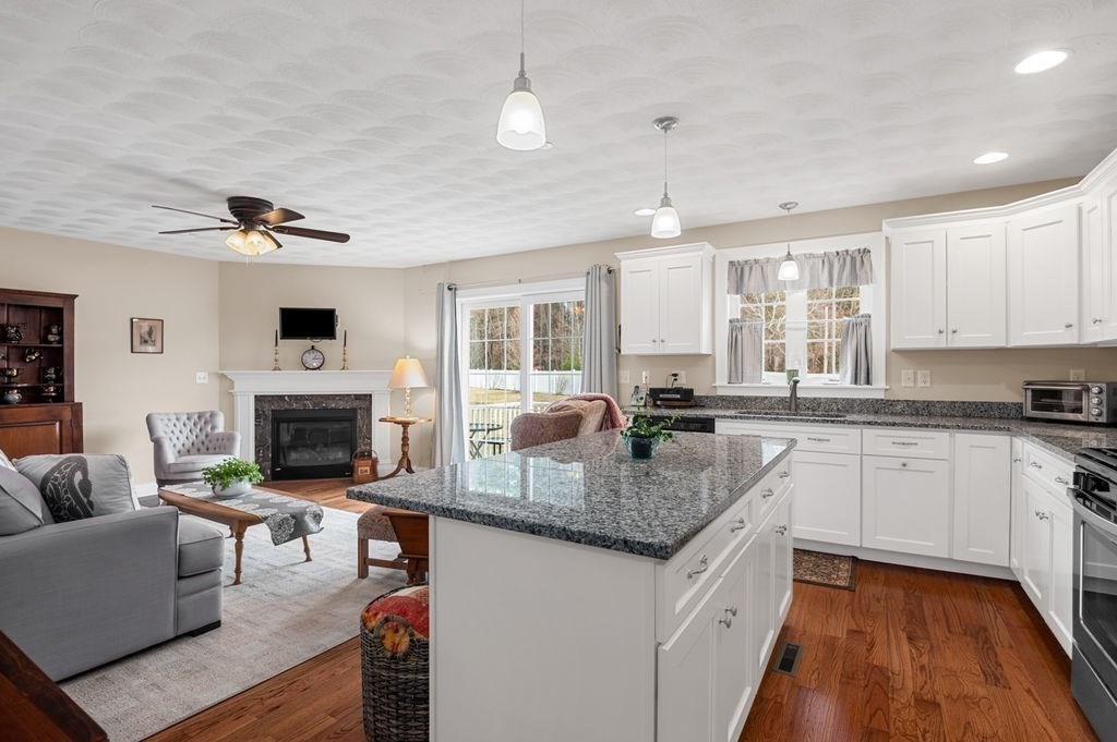 13 Freedom Way, Unit 13 Merrimac, MA 01860 - Photo 7 of 26 a kitchen with granite countertop a stove a sink dishwasher and white cabinets with wooden floor