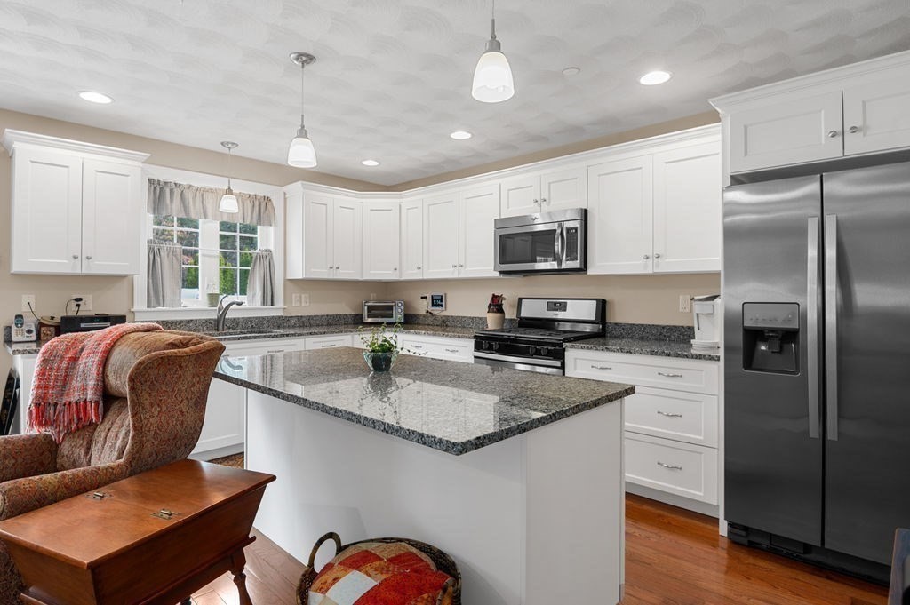 13 Freedom Way, Unit 13 Merrimac, MA 01860 - Photo 8 of 26 a kitchen with stainless steel appliances granite countertop a sink a stove a refrigerator cabinets and a dining table with wooden floor