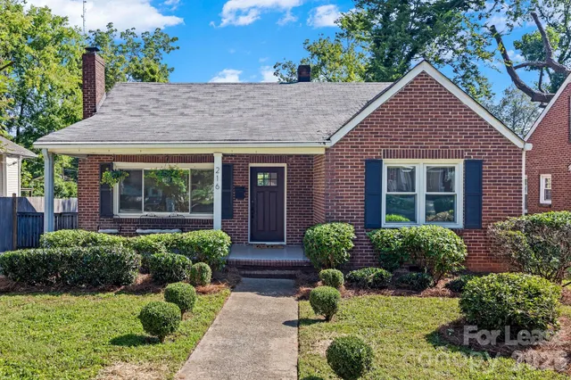 a front view of a house with a yard and potted plants