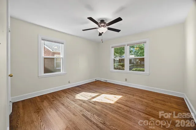 a view of empty room with wooden floor and fan