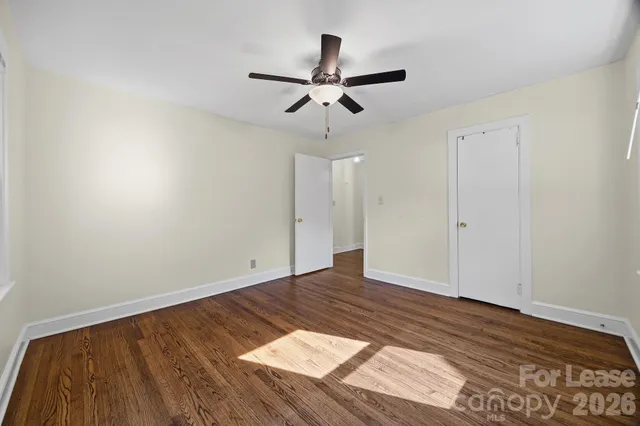 a view of empty room with wooden floor and ceiling fan