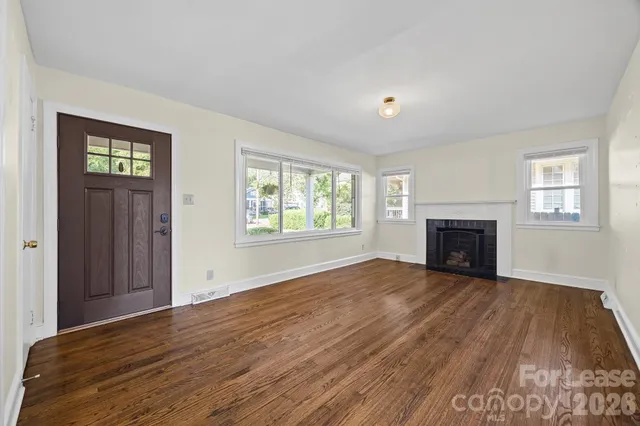 an empty room with windows and fireplace